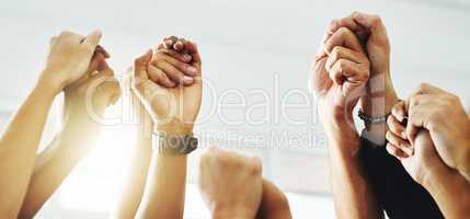 Were stand strong and tall. Closeup shot of a group of unrecognizable businesspeople holding hands while raising their arms.