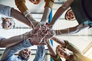 The supportive team is a strong team. Low angle shot of a group of colleagues joining their hands in solidarity at work.