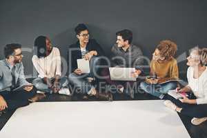 Discussing and researching ideas at the same time. Studio shot of a diverse group of creative employees having a meeting inside.