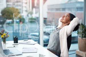 More success, less stress. Shot of a young businesswoman relaxing at her desk in a modern office.