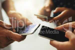 Get connected and stay in the know. Closeup shot of a group of unrecognizable businesspeople using their cellphones in synchronicity.