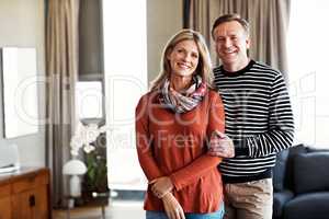 Home is where the heart is. Portrait of a happy mature couple standing in their living room.