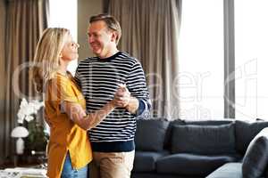 Dancing in the living room. Shot of an affectionate mature couple dancing in their living room.