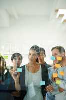 Planning is the first step. Cropped shot of a group of young designers planning on a glass board.