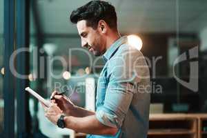 One device, so many supportive functions. Shot of a young businessman using a digital tablet in a modern office.