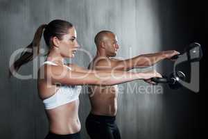 Training to become fighting fit. A man and woman working out with kettle bells at the gym.