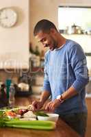 Making a healthy meal from scratch. Shot of a happy young man preparing a healthy snack at home.