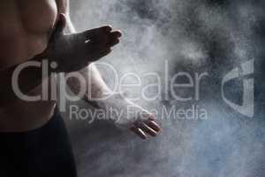 Getting ready to perform. A cropped view of a male gymnast dusting his hands with chalk.