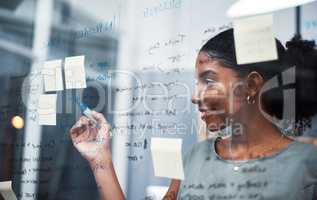 The expert mind behind an expert plan. Shot of a young businesswoman brainstorming with sticky notes on a glass screen in modern office.