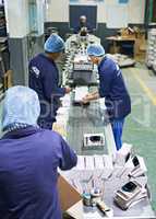 Shot of a people working inside a printing, packaging and distribution factory. The commercial designs displayed in this image represent a simulation of a real product and have been changed or altered enough by our team of retouching and design specialist