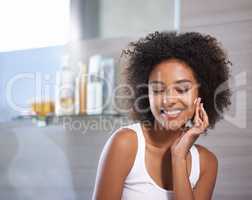 Giving my skin the VIP treatment. An attractive young woman applying cream to her face.