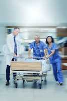 To the operating room stat. Shot of a group of medical professionals rushing a patient on a gurney down a hospital corridor.