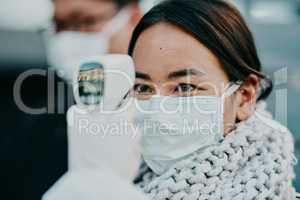 The quicker way to get results. Shot of a young woman getting her temperature taken with an infrared thermometer by a healthcare worker during an outbreak.