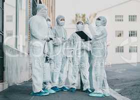 Healthcare workers are the heroes of this story. Shot of a group of healthcare workers wearing hazmat suits working together during an outbreak in the city.