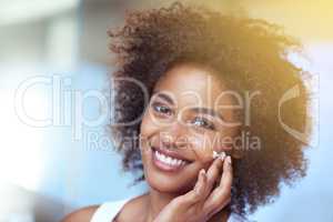 Soft skin keeps me smiling. Cropped portrait of a young woman moisturizing her face in the bathroom.