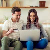 Shop online and ditch the shopping line. Shot of a happy young couple making a credit card payment on a laptop together at home.