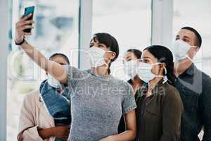 Dont let corona compromise your camaraderie. Shot of a group of young people wearing masks and taking selfies at the airport.