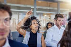 I have a question before we continue.... Shot of a young businesswoman raising her hand during a presentation in an office.