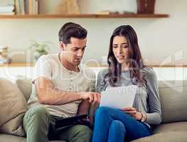 Our spending is starting to get out of hand. Shot of a young couple going through their paperwork together at home and looking worried.