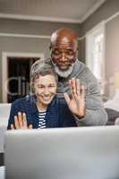 Connect to loved ones wherever you are. Shot of a senior couple waving while using a laptop at home.