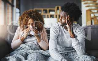 Flu season has arrived. Shot of a young man getting irritated by his girlfriend suffering with allergies at home.