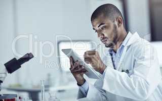 Research plays a big role in solving problems. Shot of a scientist recording his findings on a digital tablet.