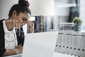 The struggle is real. Shot of a young businesswoman looking stressed while working at her desk in a modern office.