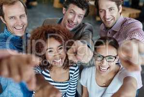 We owe our success to you. Portrait of a group of smiling coworkers pointing at the camera while standing in an office.