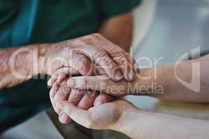 Too often we underestimate the power of a listening ear. Closeup shot of a woman holding a senior mans hands in comfort.