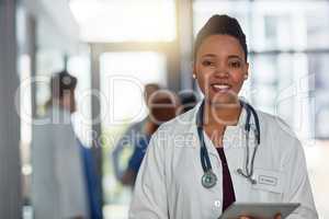 Quality healthcare is of utmost importance to me. Portrait of a young female doctor standing in a hospital with her colleagues in the background.