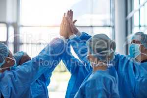 Another success means another life saved. Cropped shot of a team of medical practitioners high fiving together in a hospital.
