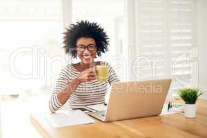 Nothing like a cup of comfort to start the day. Portrait of a young woman drinking coffee while working on her laptop at home.