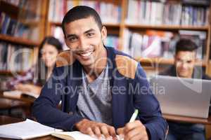 Hes such a diligent student. Cropped portrait of a handsome young student working diligently in his classroom.