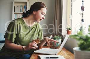 This is exactly what I need. Cropped shot of an attractive young businesswoman sitting alone in her home office and using her laptop for online shopping.