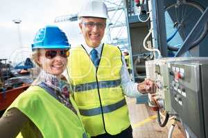 Working together leads to growth in the company. Two engineers standing near a power supply unit with broad smiles.