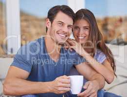 Total contentment. Shot of an affectionate young couple relaxing on the patio with coffee.