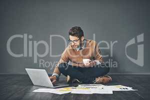 Who said an informal environment cant be a productive one. Studio shot of a young businessman working on a laptop against a grey background.