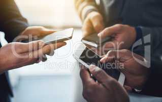 Its vital to stay updated in a connected world. Shot of a group of unrecognisable businesspeople using their cellphones in synchronicity.