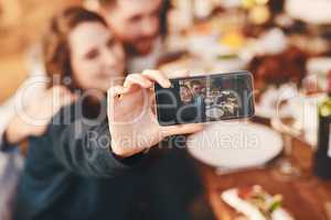 Having a good time with the ones I love. Cropped shot of a young woman taking a selfie while at a dinner party.