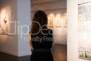 Taking in a century of art. Shot of a young woman looking at paintings in a gallery.