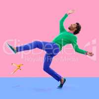 Watch your step.... Humorous shot of a young man slipping on a banana peel agains a colorful studio background.