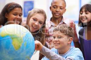 Here it is - Geography class. A group of pupils looking at a globe during geography class.