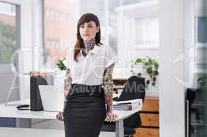 Shes ready to rock the corporate scene. A tattoo-covered young businesswoman in her office.