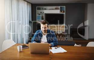 Its still business as usual even at home. Shot of a handsome young businessman sitting down and using his laptop to take a video call while working from home.