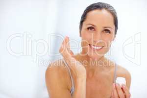 Adding a touch of moisture. Shot of an attractive mature woman applying moisturizer to her skin.