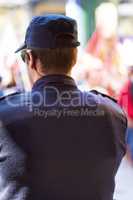 Keeping it legal. Rearview shot of a policeman keeping watch over a group of protesters.