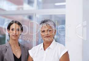 They make an excellent team. Portrait of two businesswomen standing beside each other in an office.