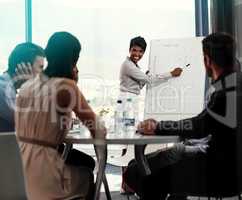Allow me to direct your attention here.... Shot of a businesswoman giving a whiteboard presentation to a group of colleagues in a boardroom.