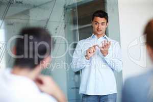 There are several points to remember.... Attractive casual businessman giving a presentation using a glass window for demonstration.