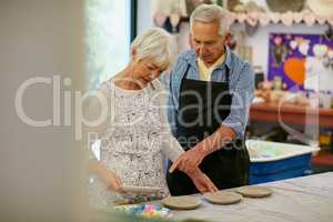 Thats an interesting pattern on that plate. Shot of a senior couple working with ceramics in a workshop.